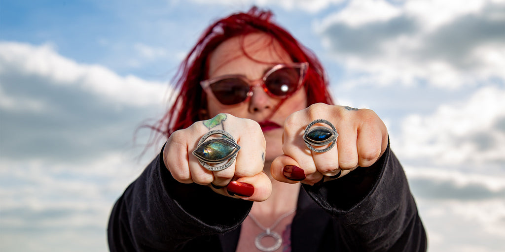 Beautiful red-haired woman wears glowing eye-shaped rings on both fists