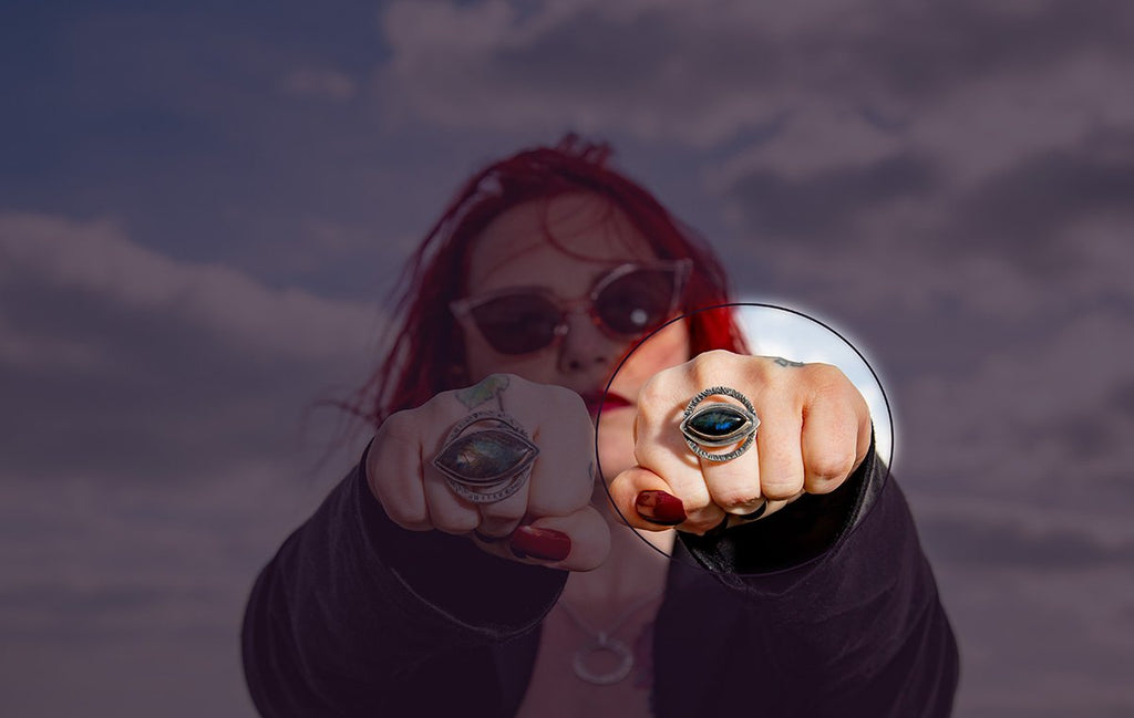 Eye-shaped glowing labradorite stone surrounded in sterling silver and a textured halo, handmade silver jewellery worn by a woman with red hair and red nails